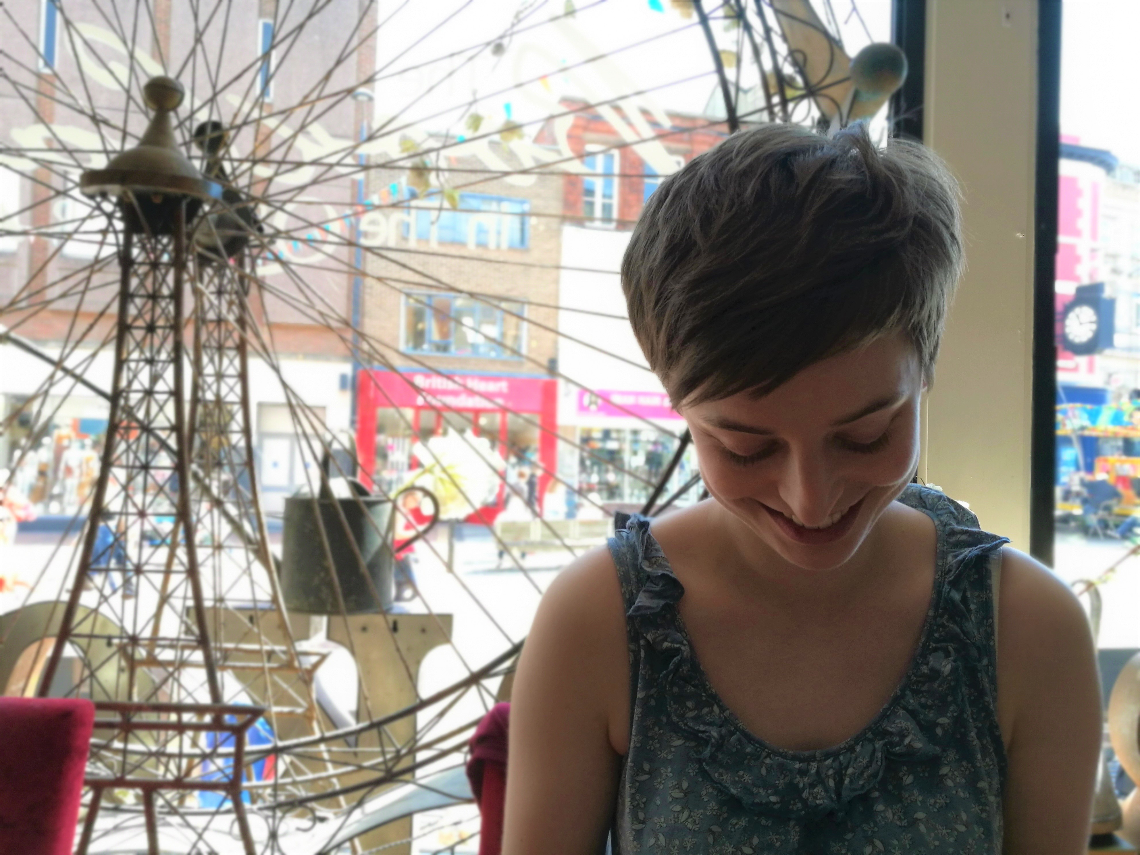 Photo of Emily Holyoake, a young white woman with short brown hair, smiling down at something.
